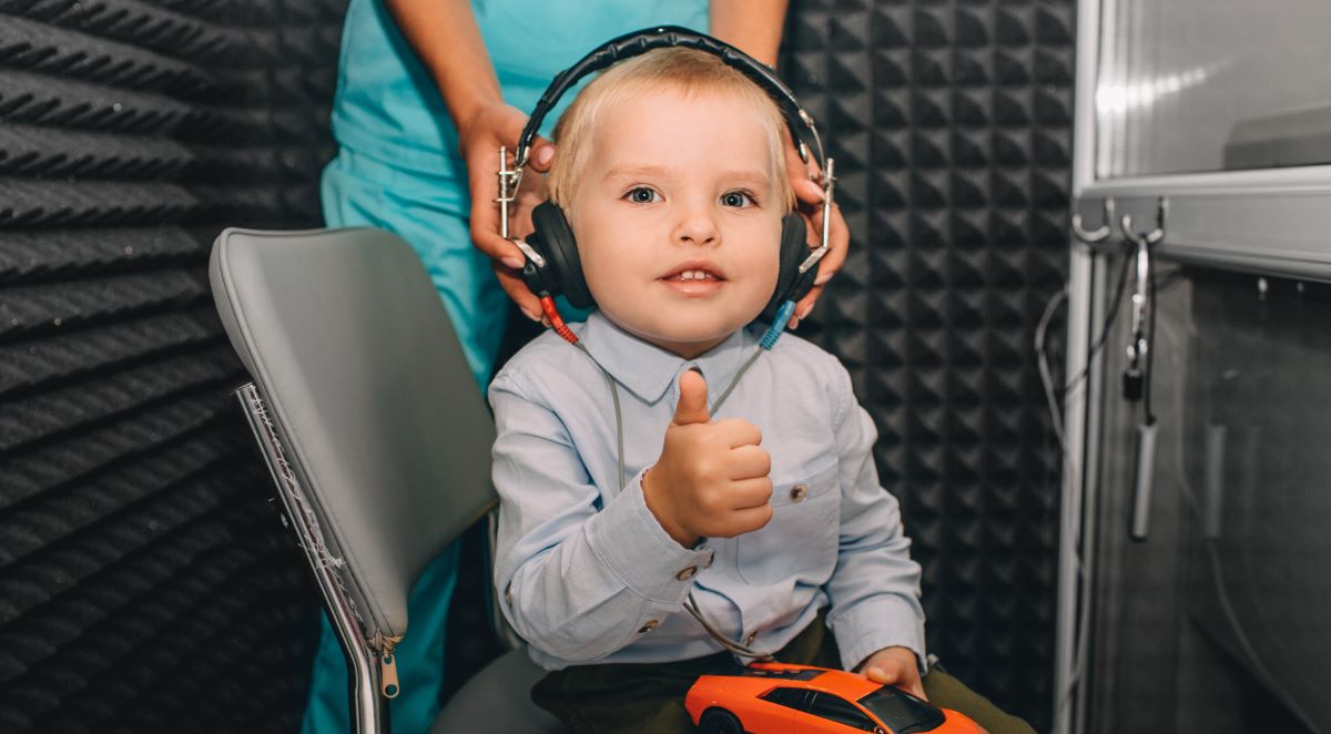 criança em cabine de audiometria